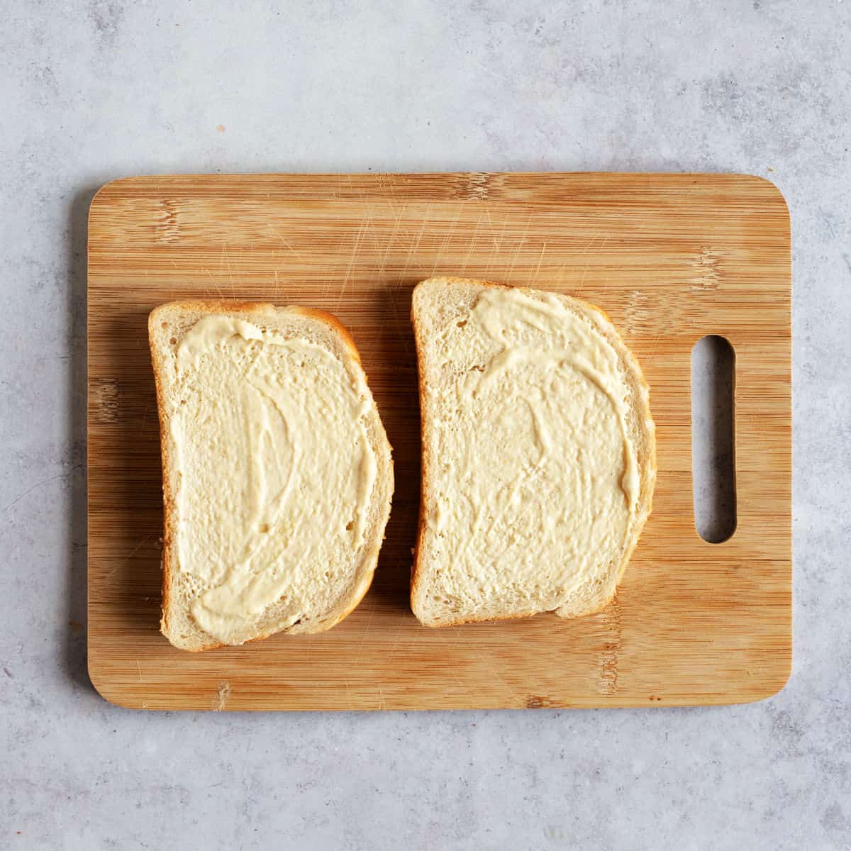 Two slices of bread spread with mustard mayo.