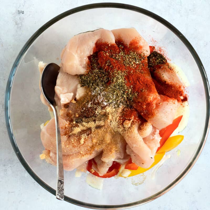 Chicken and seasonings in a bowl.