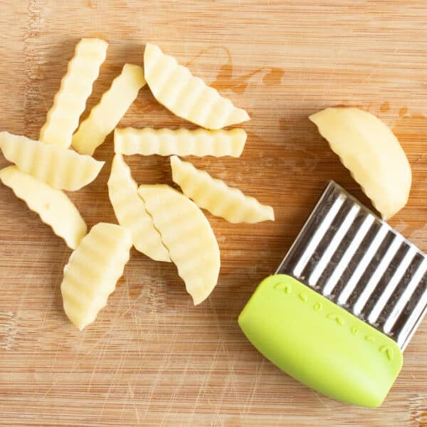 Cutting potatoes into chips on a chopping board.