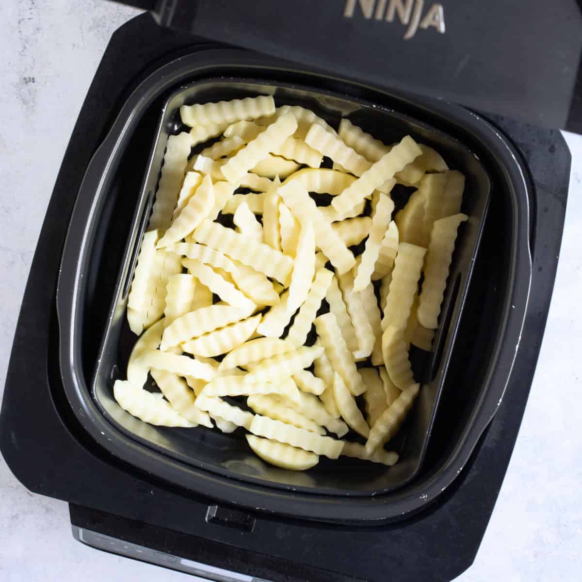 Uncooked chips in air fryer basket.