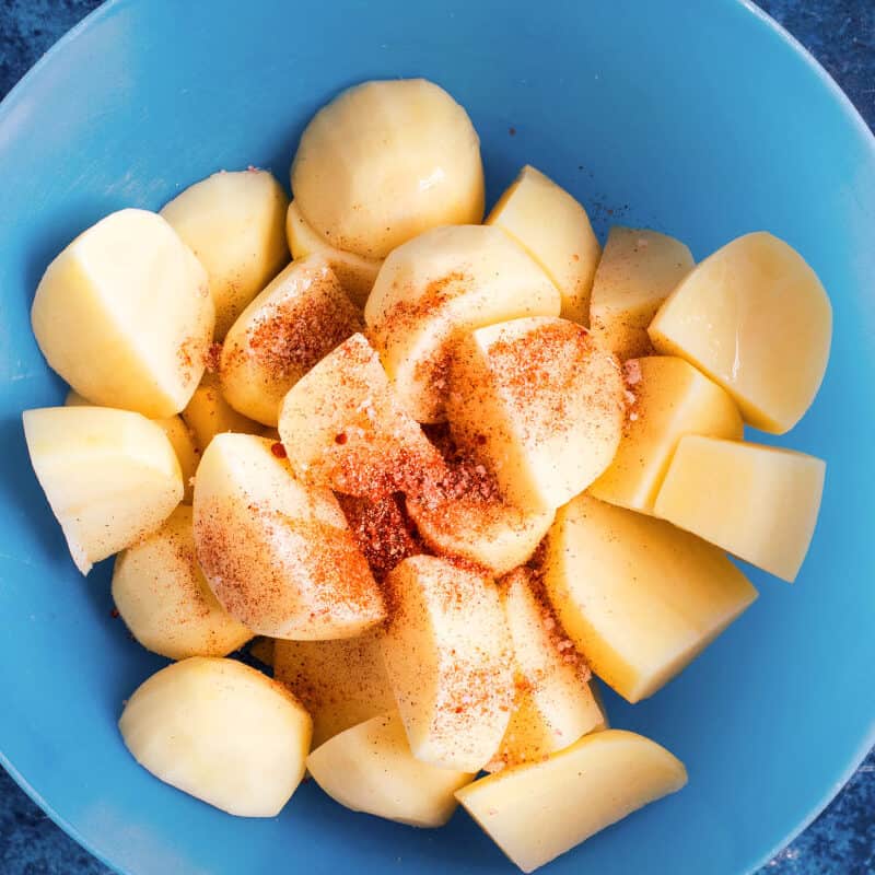 Potatoes in a bowl with seasonings.