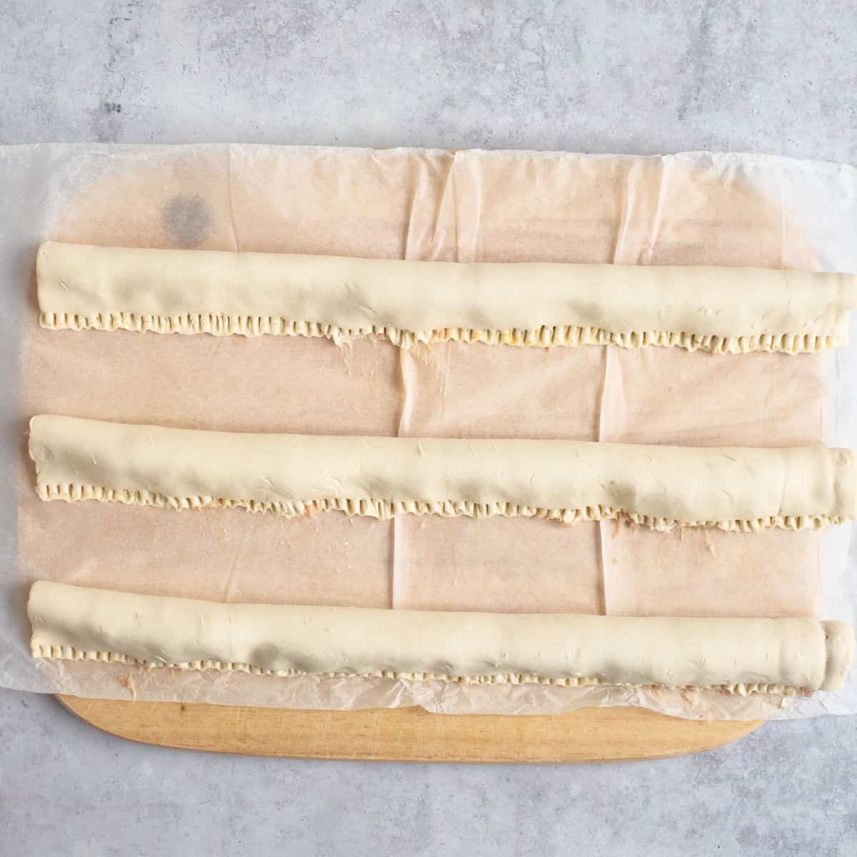 Making sausage rolls on a wooden board.