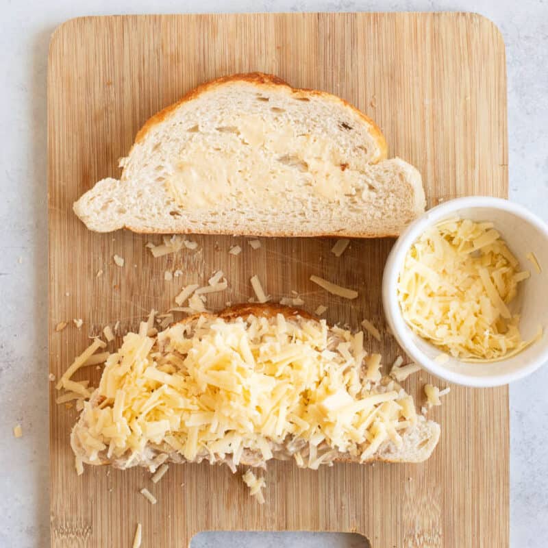 Grated cheese on top of tuna and a slice of bread.