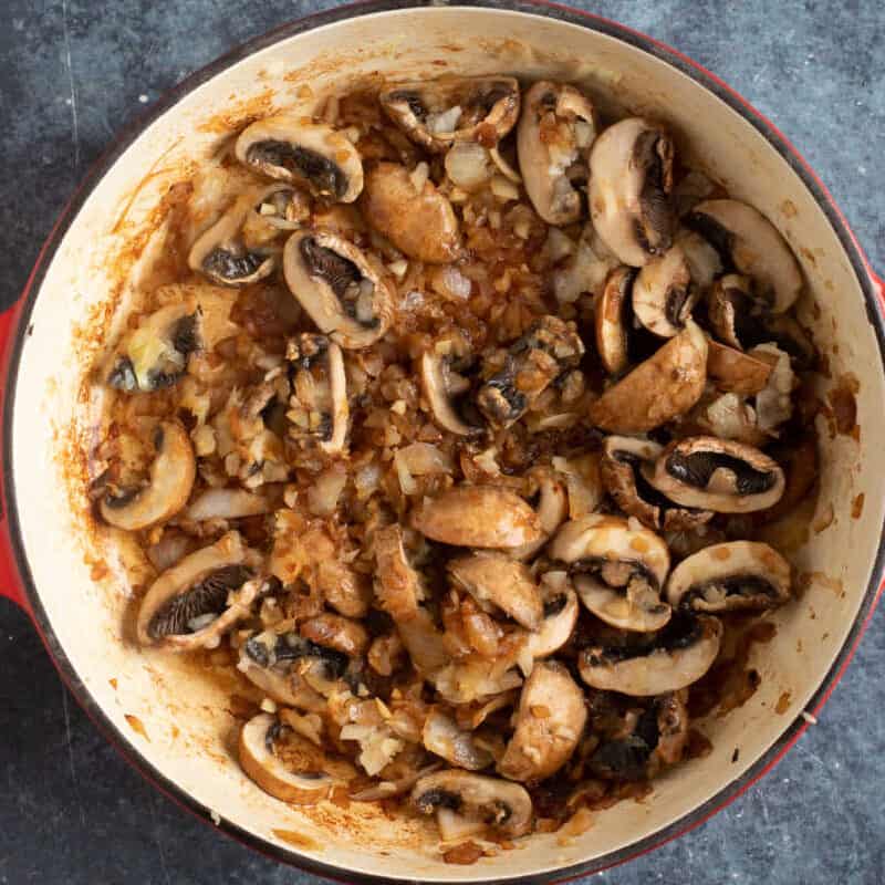 Sliced mushrooms cooking in a pan.