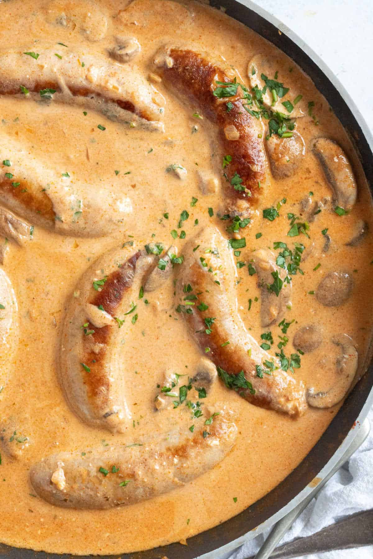 Sausages and mushroom stroganoff in a pan.