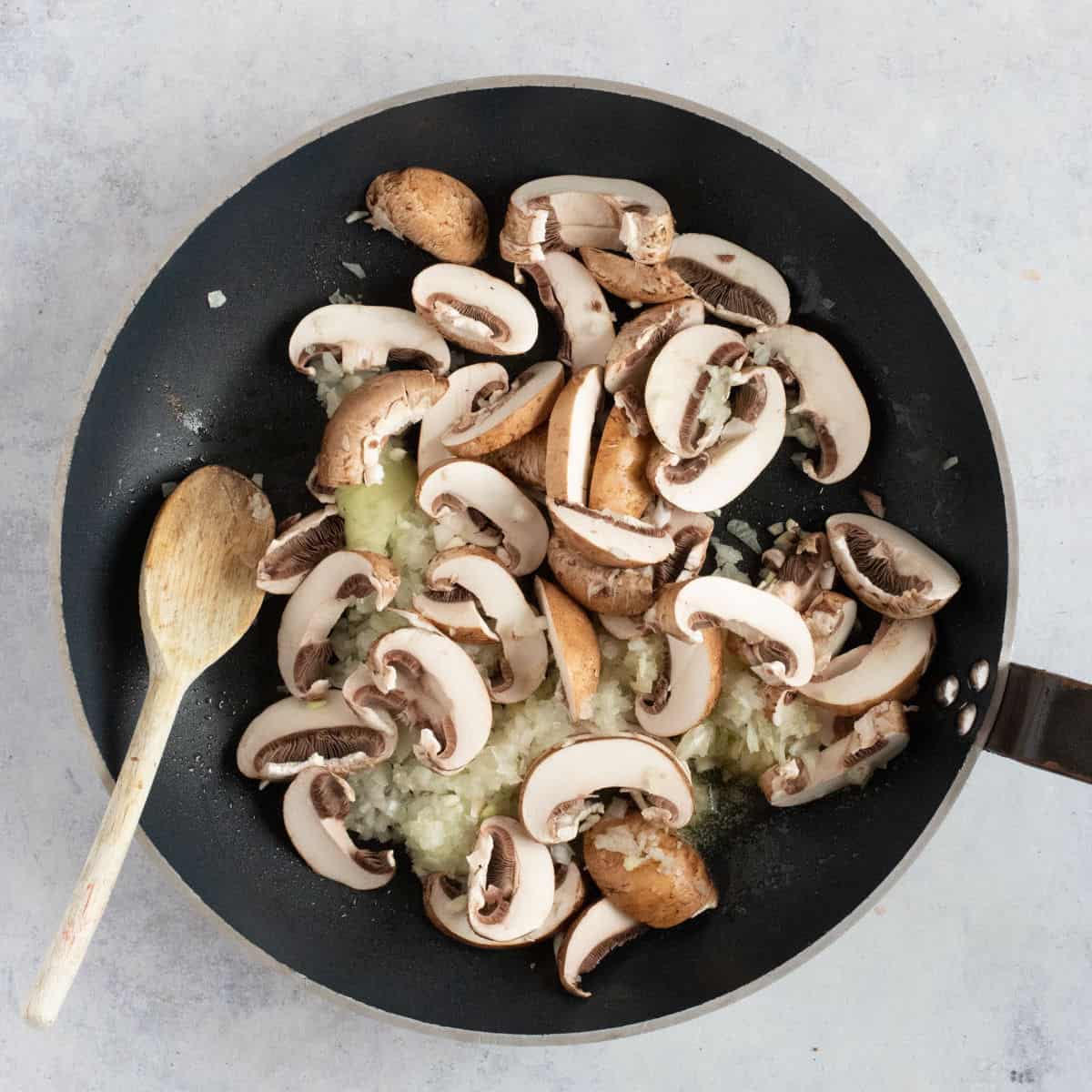 Onions and sliced mushrooms in a pan.