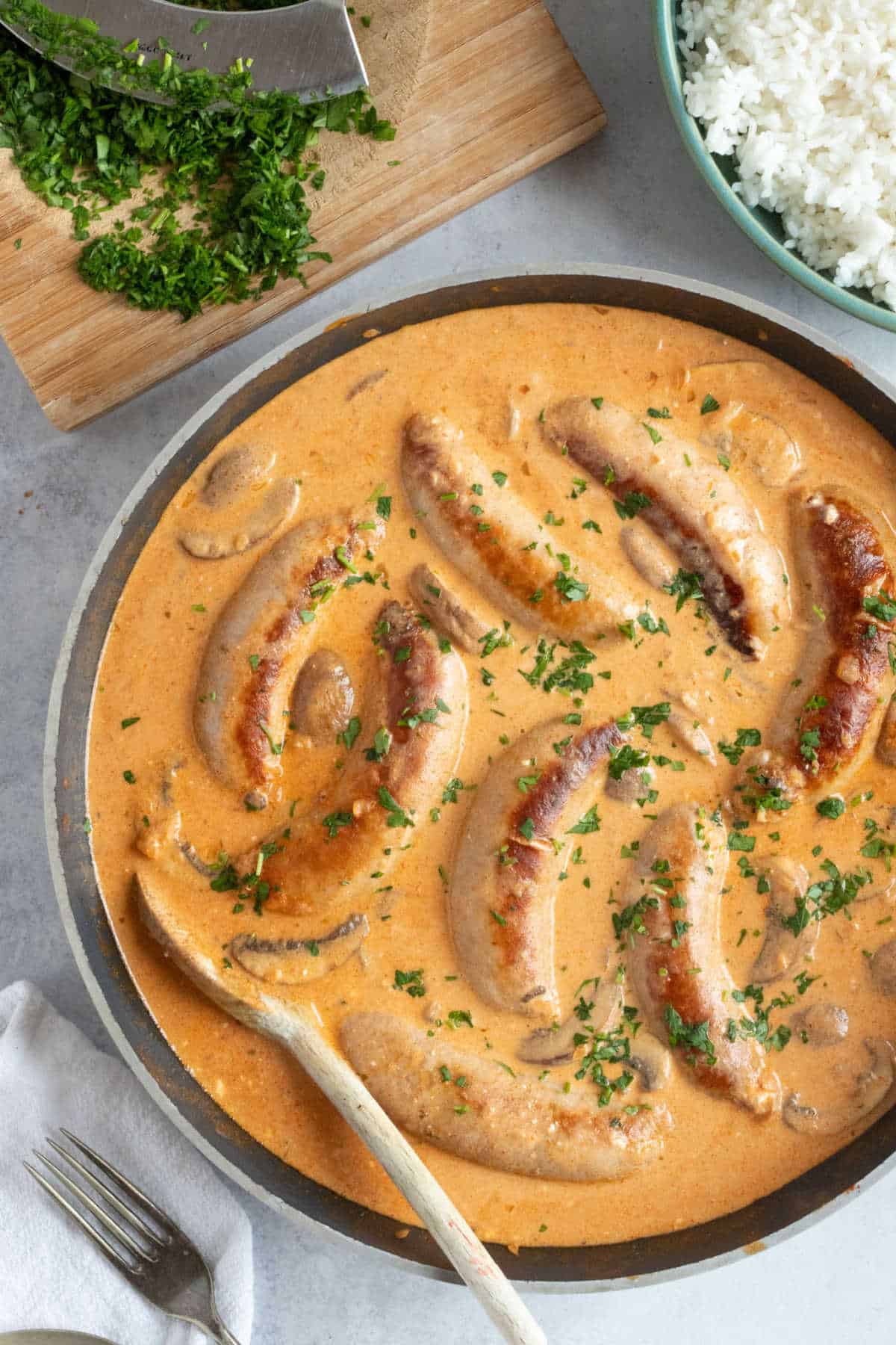 A pan of sausage stroganoff with a side of rice.