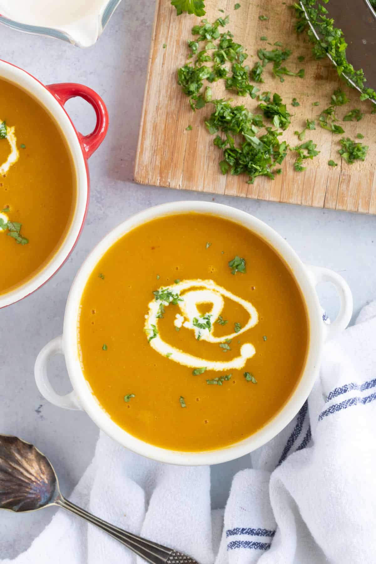 A bowl of spiced carrot and parsnip soup garnished with parsley.