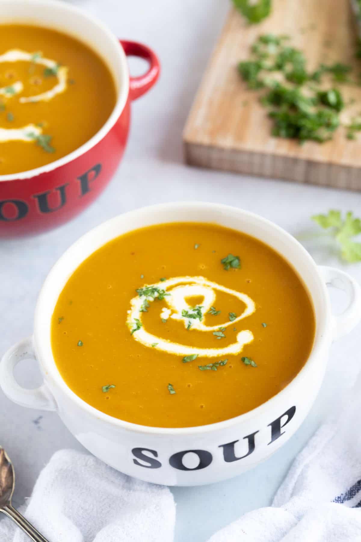 A bowl of carrot and parsnip soup swirled with double cream and sprinkled with chopped parsley.