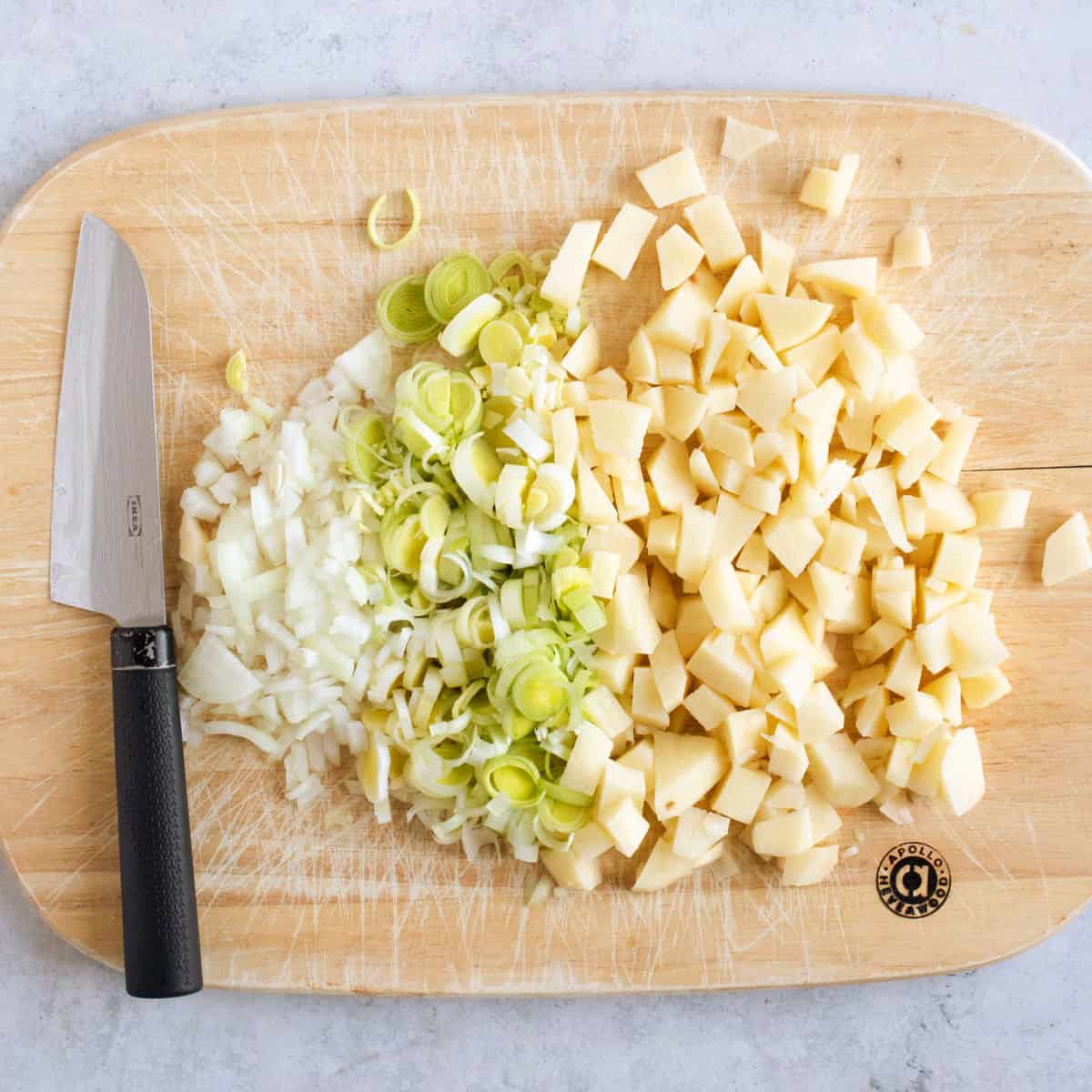 Chopped potato and leeks on a chopping board.