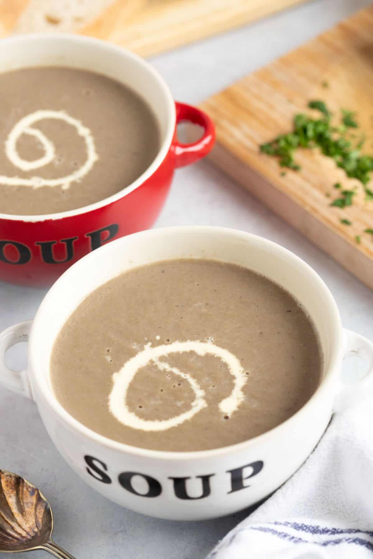 A bowl of mushroom soup with a drizzle of cream on top.