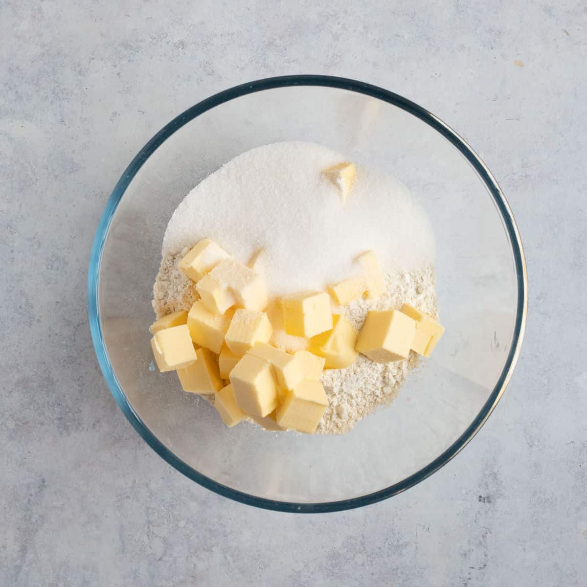 Cubed butter, flour and sugar in a bowl.