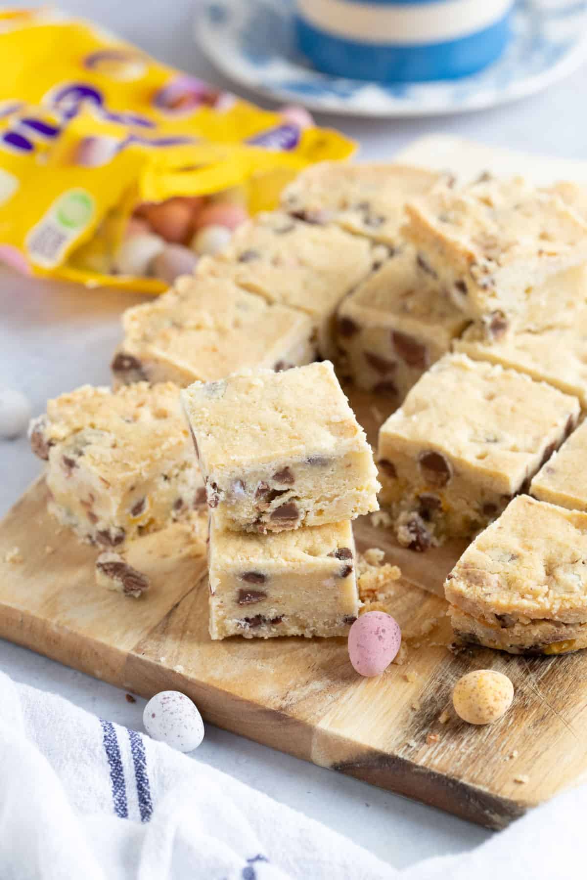 Mini egg shortbread squares on a wooden board.