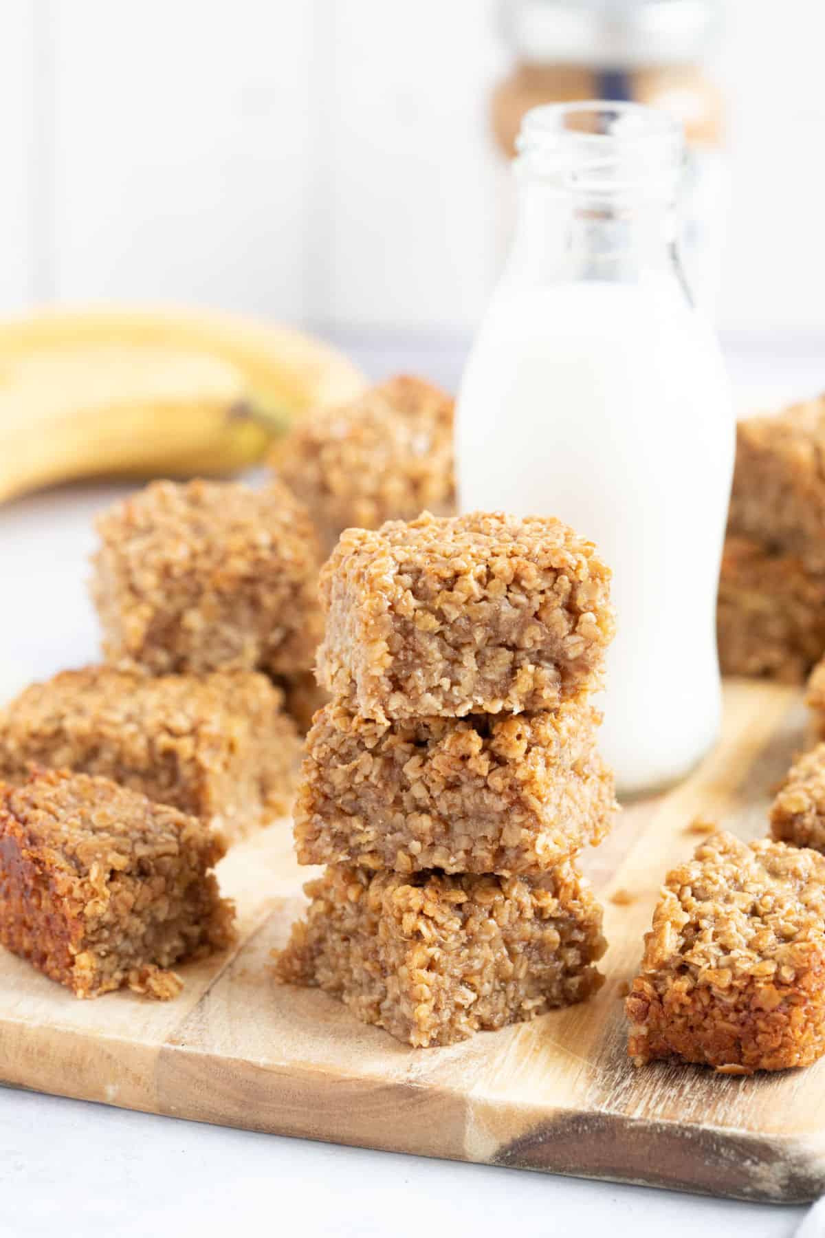 A stack of banana peanut butter and honey flapjacks with a glass of milk behind.