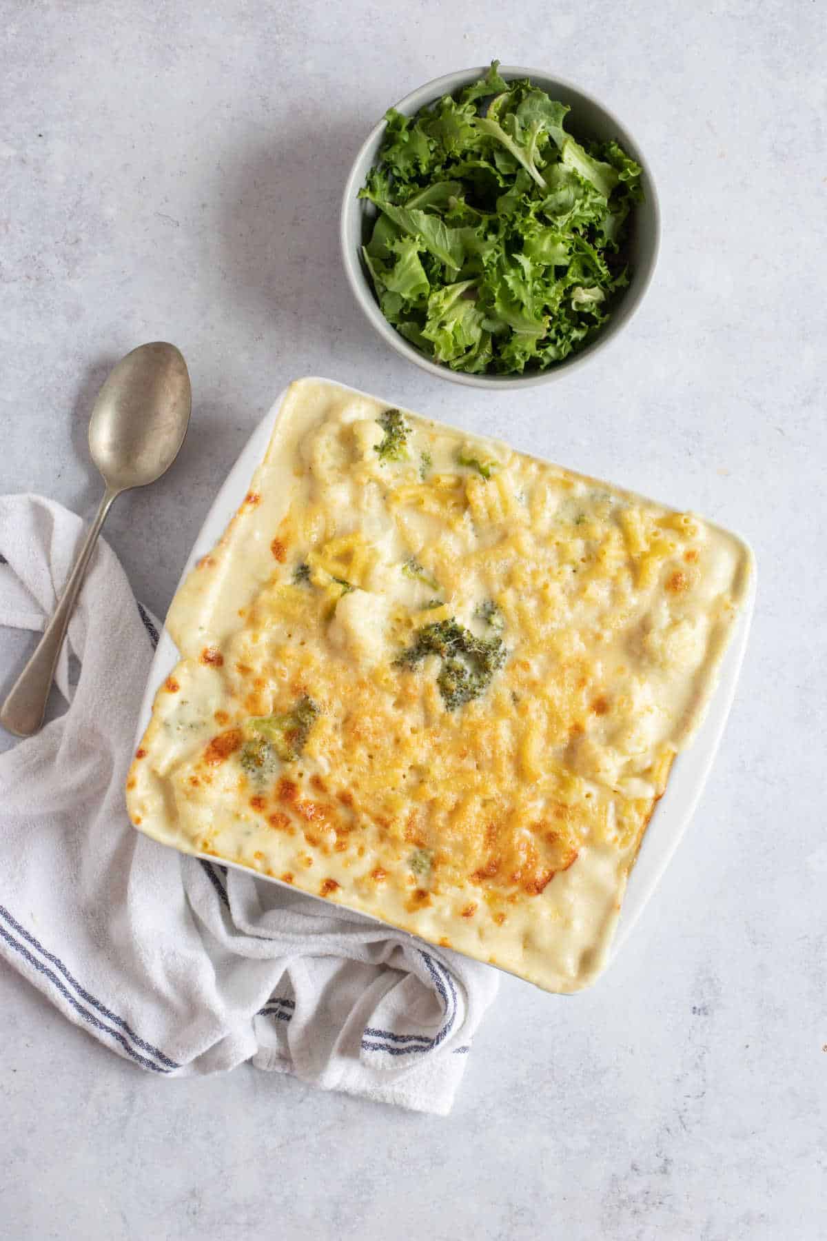 Cauliflower and broccoli macaroni cheese with a bowl of salad.