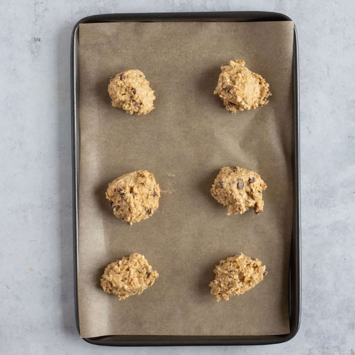 Unbaked banana oat cookies on a baking sheet.