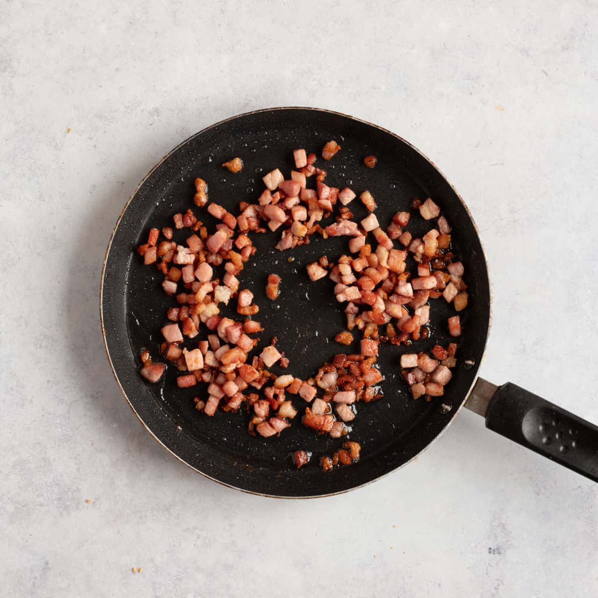 Bacon lardons in a frying pan.