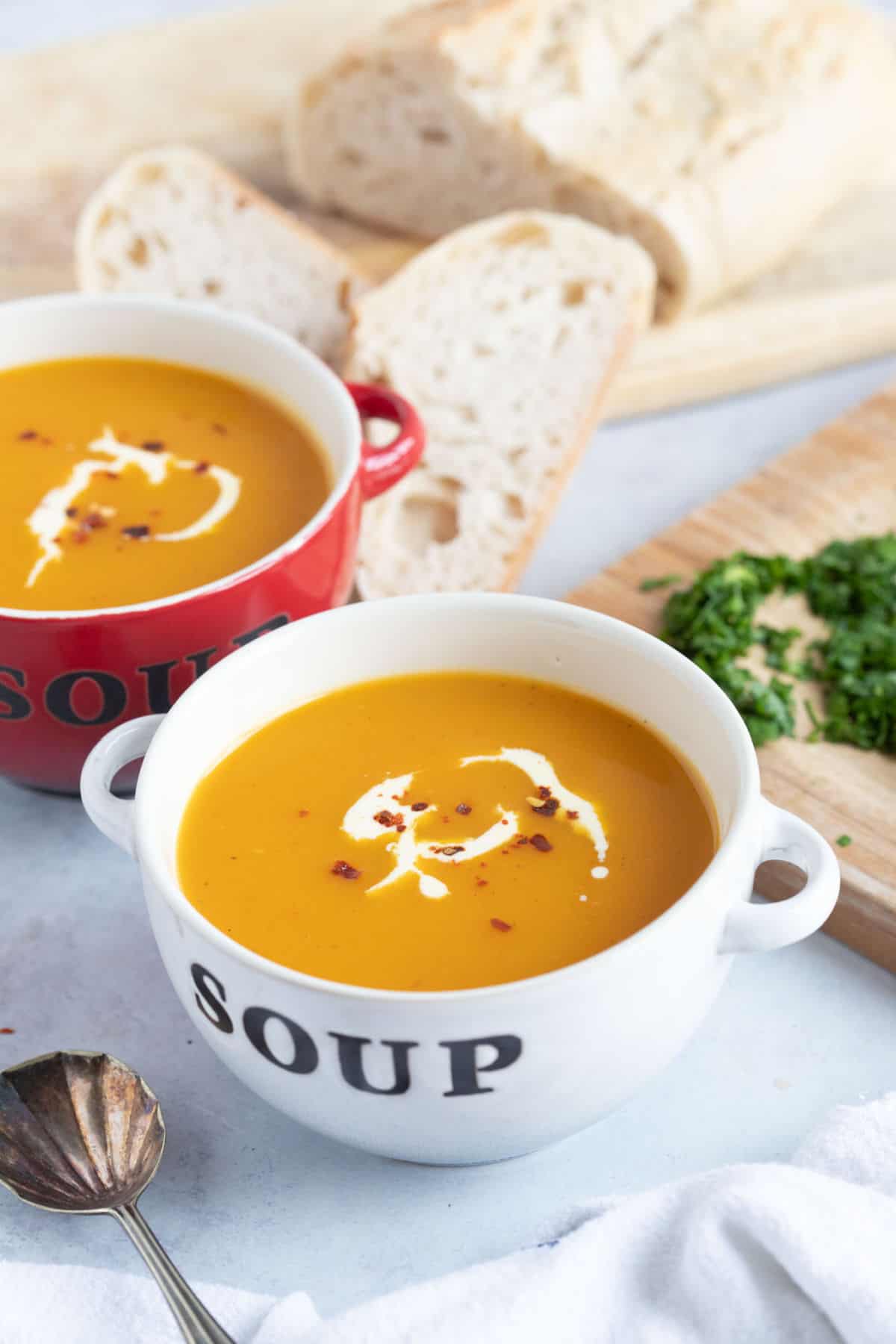 A bowl of butternut squash and sweet potato soup with bread.