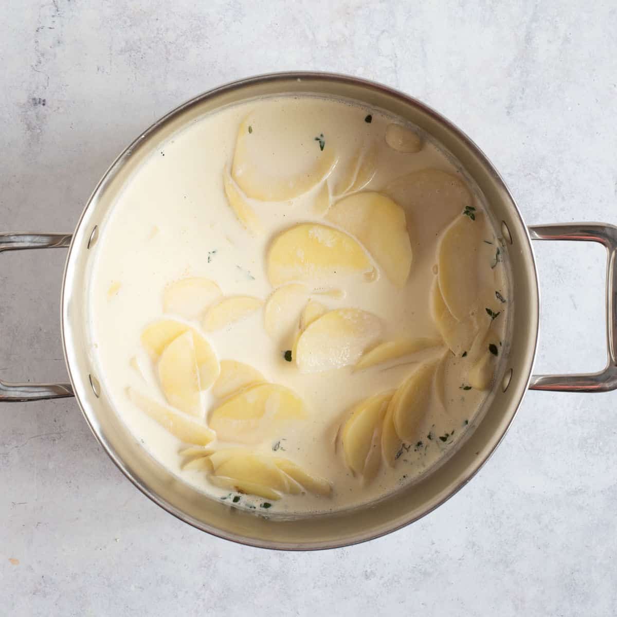 Sliced potatoes in a pan with milk and cream.