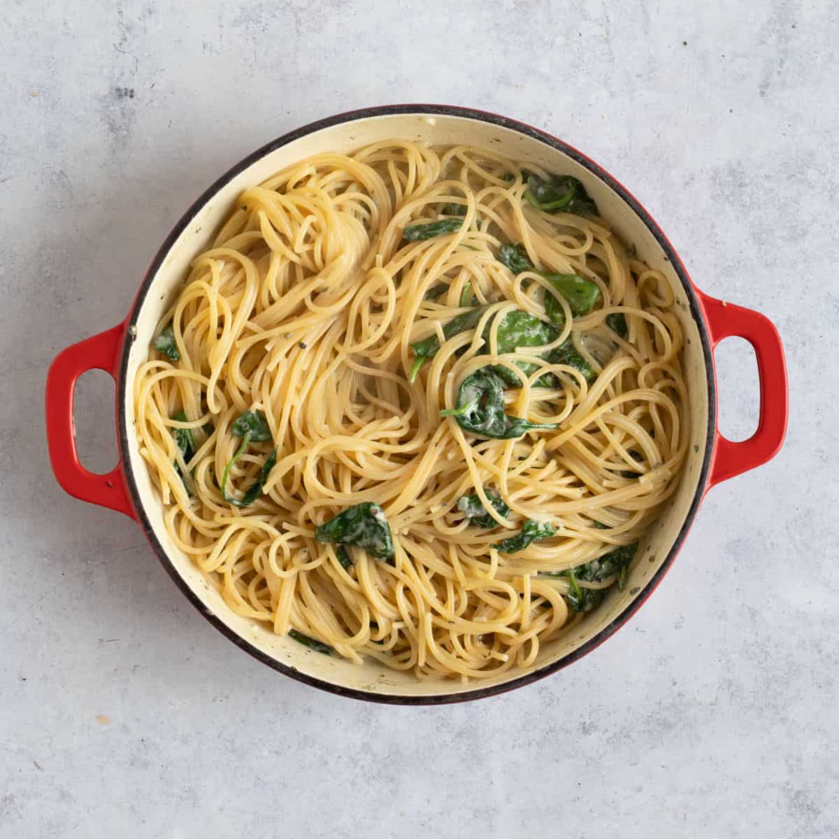 Spinach and blue cheese pasta in a red pan.