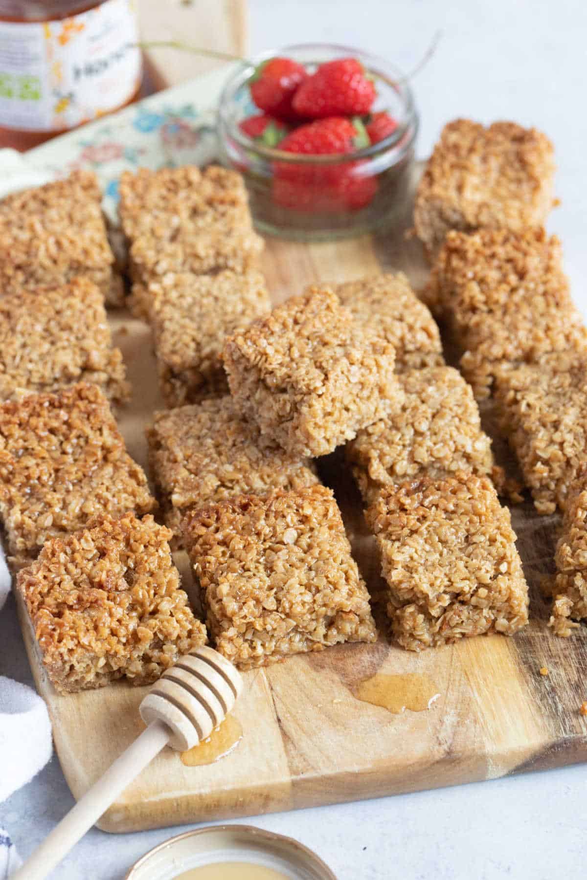 Honey flapjacks on a wooden board with strawberries.