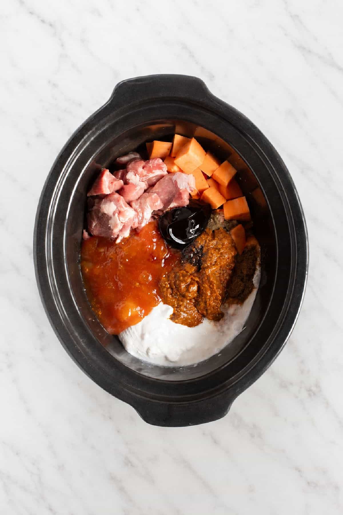 Lamb curry ingredients in slow cooker basin.