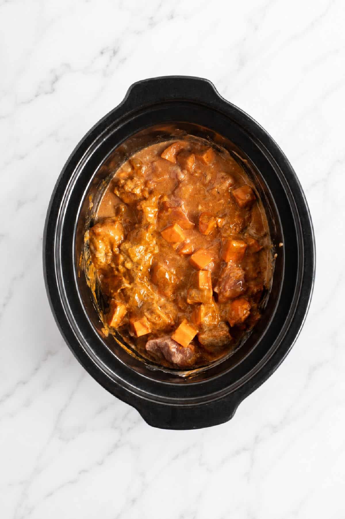 Lamb curry ingredients mixed in slow cooker.