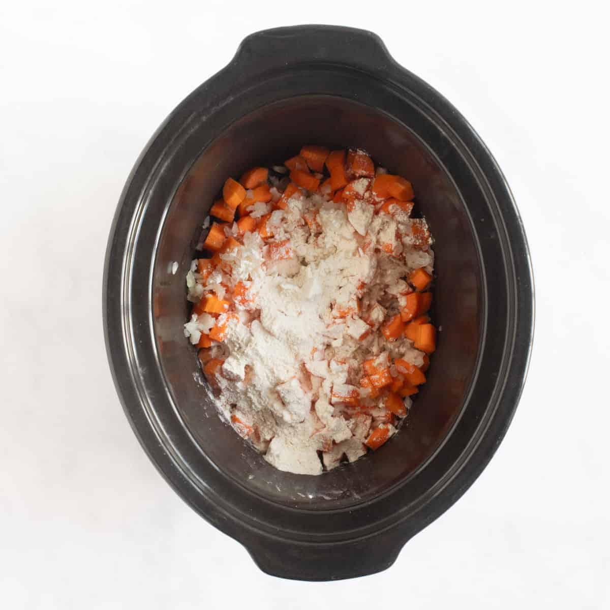 Onions and carrots in slow cooker bason.