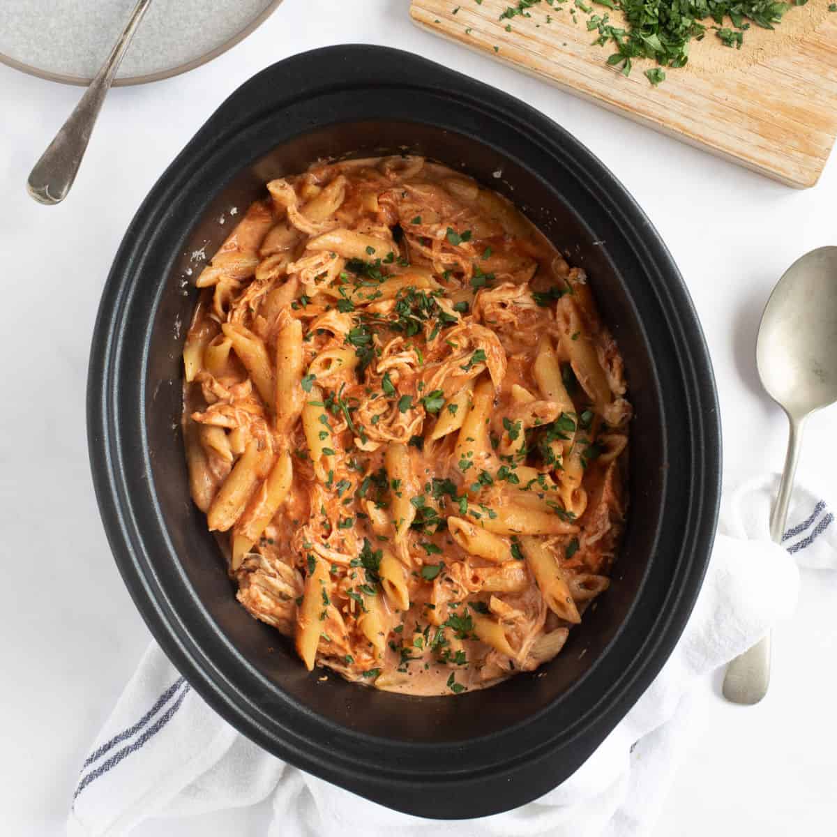 Slow cooker chicken pasta sprinkled with parsley.